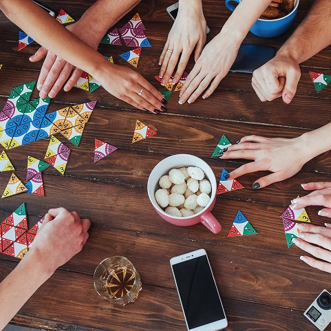 groep mensen speelt samen een kleurrijk bordspel aan tafel van bovenaf gezien